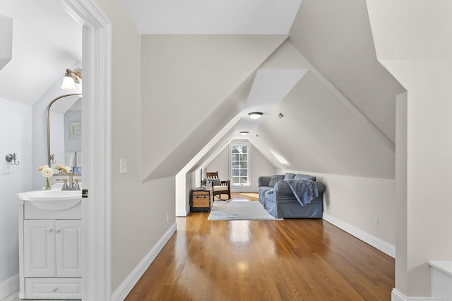 additional living space with lofted ceiling, a sink, baseboards, and wood finished floors