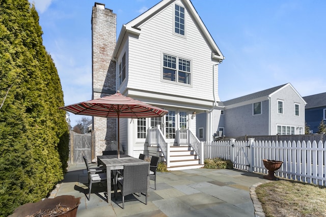 back of house with outdoor dining area, a patio, a chimney, a gate, and a fenced backyard