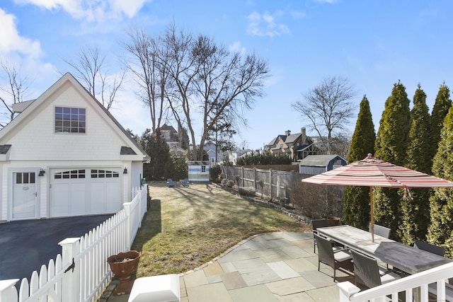 exterior space with fence private yard, outdoor dining area, a patio area, and a detached garage