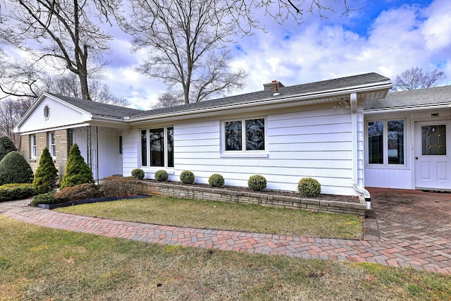 single story home featuring a chimney and a front lawn