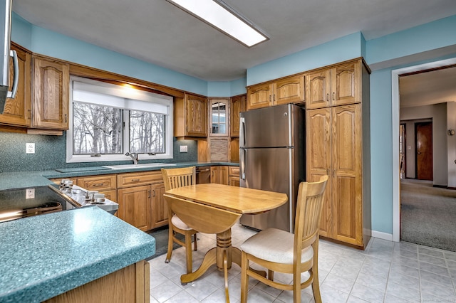 kitchen featuring brown cabinets, tasteful backsplash, and freestanding refrigerator