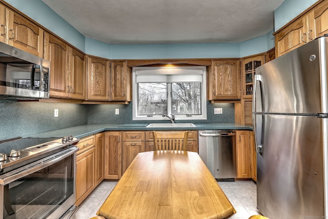 kitchen with a sink, brown cabinets, butcher block countertops, and appliances with stainless steel finishes