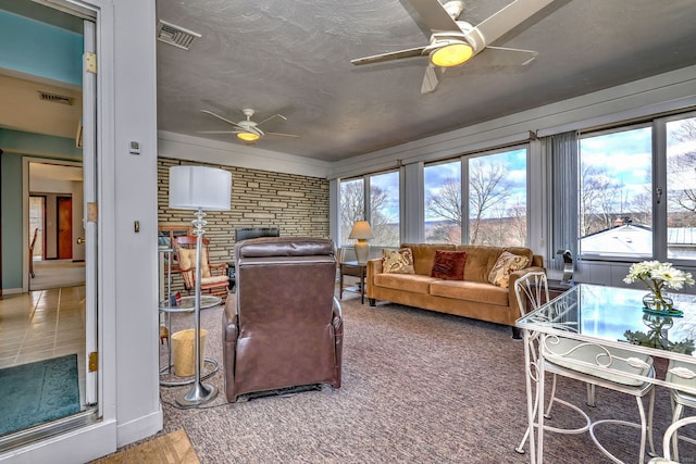 living area featuring visible vents, a textured ceiling, and a ceiling fan