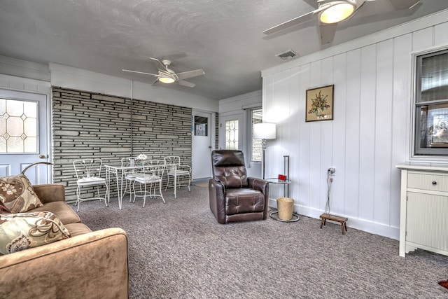 carpeted living room with visible vents, a textured ceiling, and a ceiling fan