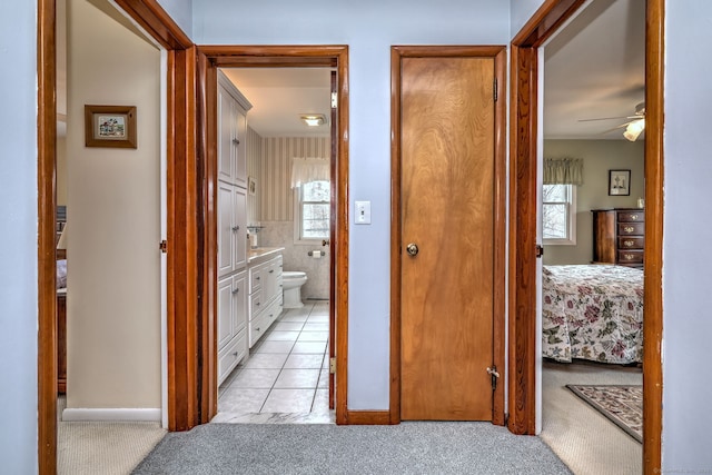 hallway featuring light tile patterned flooring and light carpet