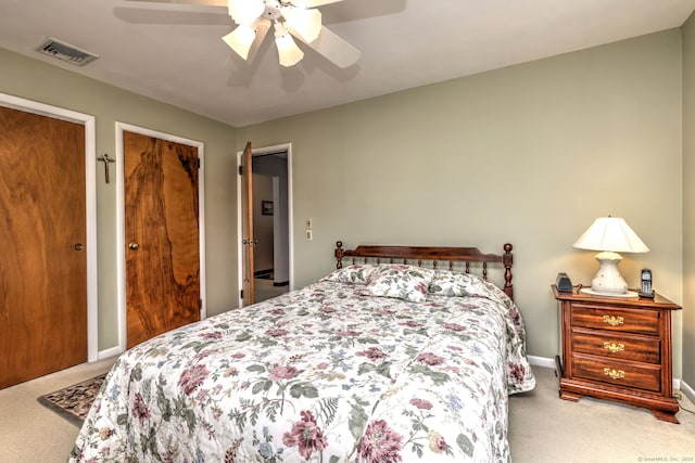 bedroom with visible vents, carpet flooring, two closets, and ceiling fan