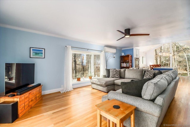 living area with an AC wall unit, crown molding, light wood-style floors, and ceiling fan