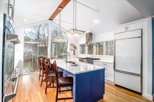 kitchen featuring light wood-style flooring, a sink, stove, built in refrigerator, and island range hood