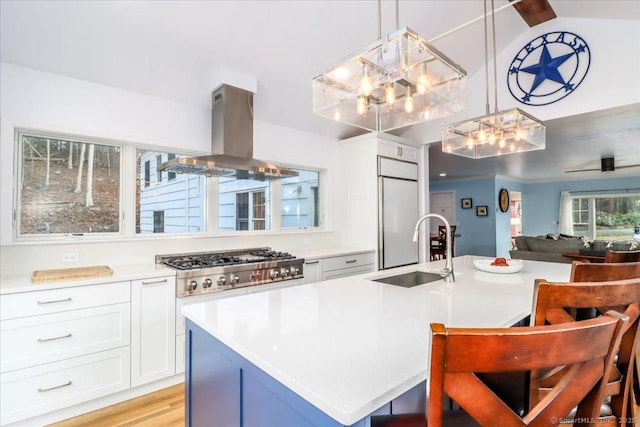 kitchen with a sink, open floor plan, built in fridge, island range hood, and stainless steel gas cooktop