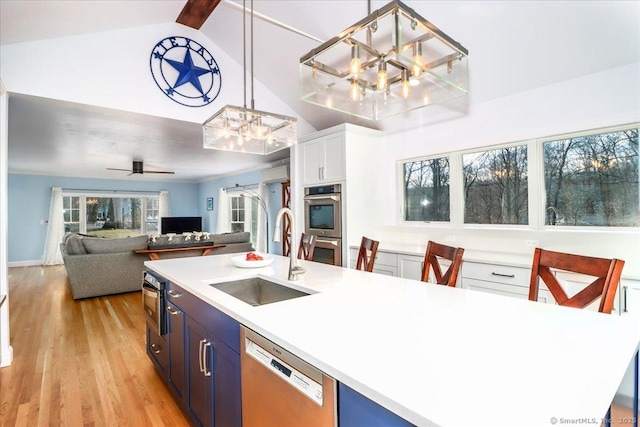 kitchen featuring a sink, light countertops, appliances with stainless steel finishes, ceiling fan with notable chandelier, and light wood-type flooring