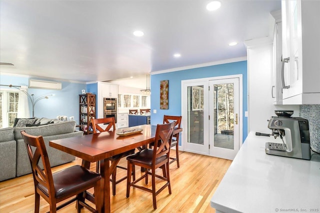 dining room featuring plenty of natural light, an AC wall unit, light wood-style floors, and ornamental molding