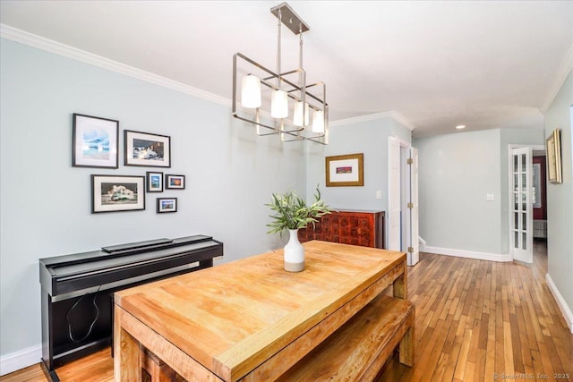 dining room with an inviting chandelier, crown molding, light wood-style flooring, and baseboards