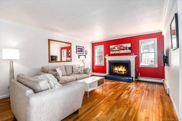 living area featuring a baseboard heating unit, light wood-style floors, a lit fireplace, a baseboard radiator, and baseboards