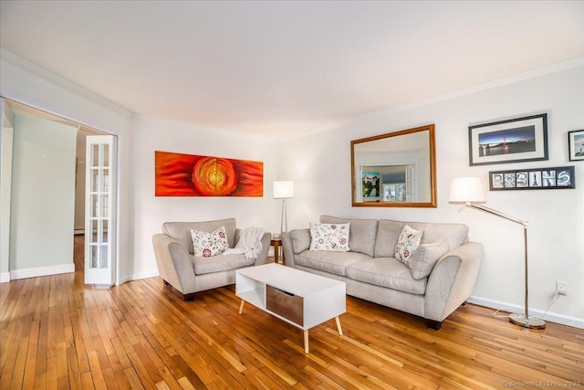 living area featuring crown molding, baseboards, and wood-type flooring