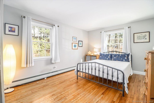 bedroom featuring a baseboard heating unit, baseboards, and hardwood / wood-style floors