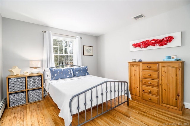 bedroom featuring visible vents, wood-type flooring, and a baseboard radiator