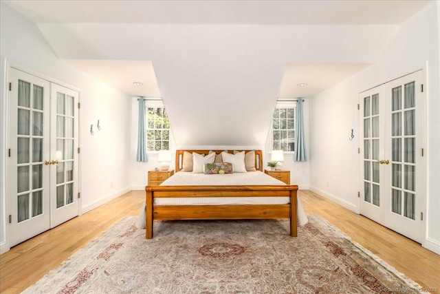 bedroom with french doors, baseboards, and wood finished floors