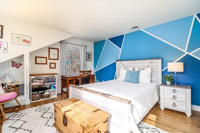 bedroom featuring visible vents, baseboards, and wood finished floors