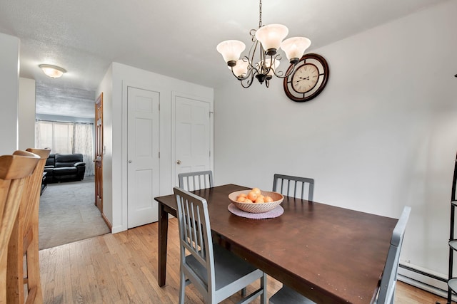 dining room featuring a baseboard radiator, a notable chandelier, light wood-style flooring, and a textured ceiling