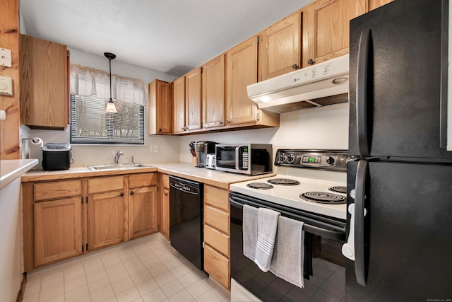 kitchen with under cabinet range hood, light countertops, hanging light fixtures, black appliances, and a sink