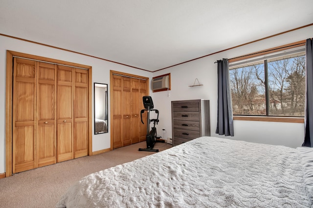 carpeted bedroom with baseboards, crown molding, multiple closets, and a wall unit AC