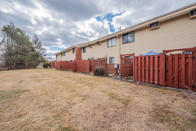 rear view of property featuring a yard, fence, and brick siding