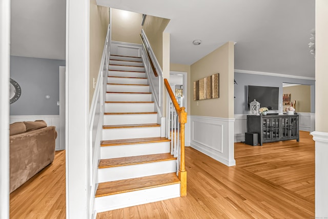 staircase with a wainscoted wall and wood finished floors