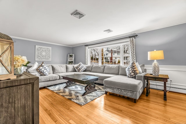 living area featuring hardwood / wood-style floors, visible vents, and crown molding