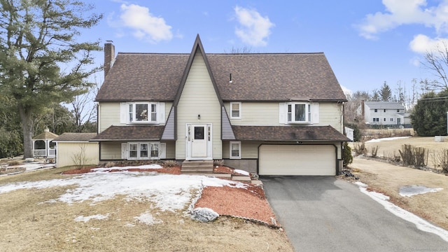 view of front of home featuring a garage, roof with shingles, aphalt driveway, and a chimney