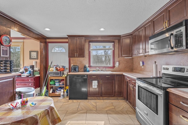 kitchen with a textured ceiling, stainless steel appliances, a sink, and light countertops