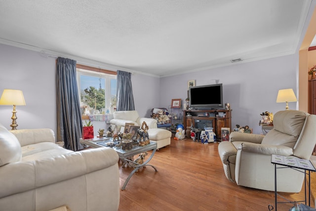 living area with crown molding, a textured ceiling, and wood finished floors