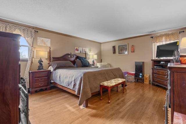 bedroom featuring ornamental molding, visible vents, and light wood-style flooring