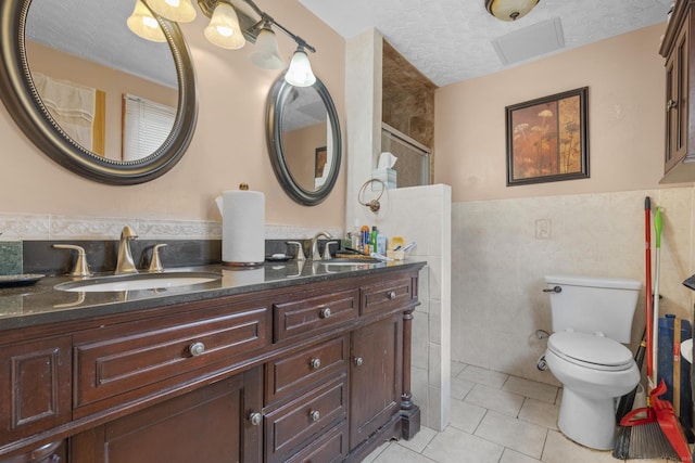 full bathroom featuring tile patterned flooring, a sink, tile walls, and a textured ceiling