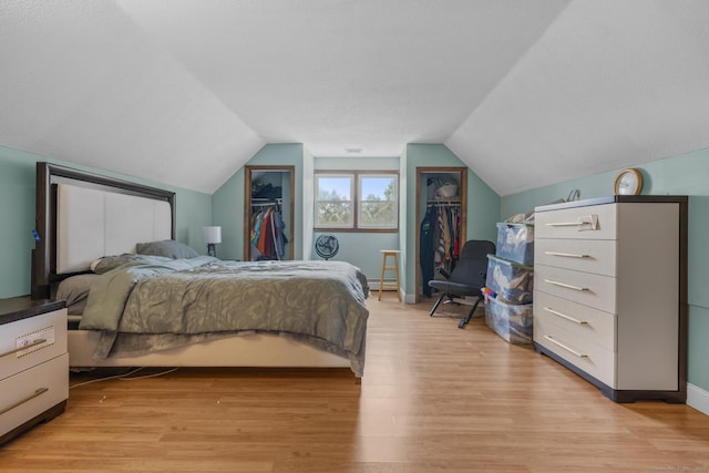 bedroom featuring vaulted ceiling, baseboards, and light wood-style floors