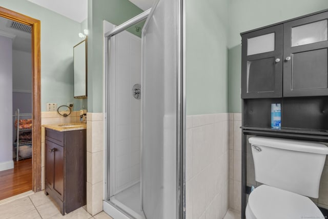 full bath with a stall shower, visible vents, toilet, tile patterned flooring, and tile walls