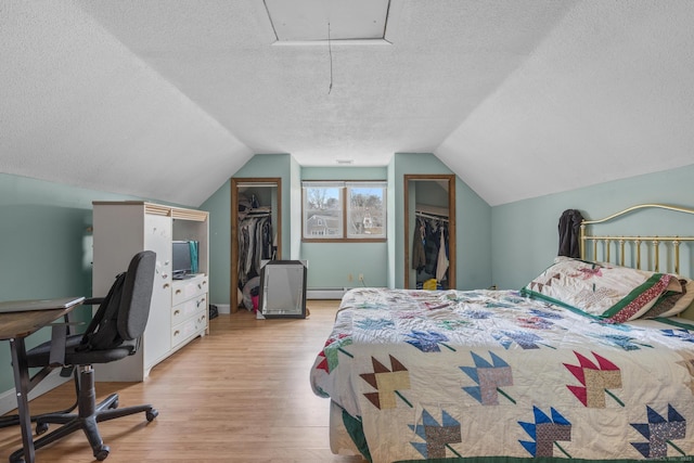 bedroom featuring attic access, baseboards, wood finished floors, vaulted ceiling, and a textured ceiling