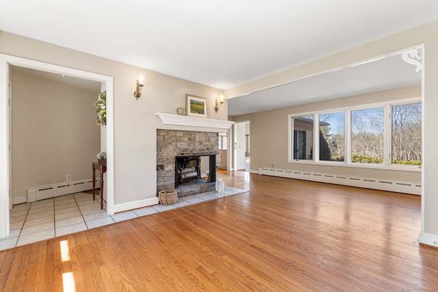 unfurnished living room with wood finished floors, a fireplace, baseboards, and a baseboard radiator