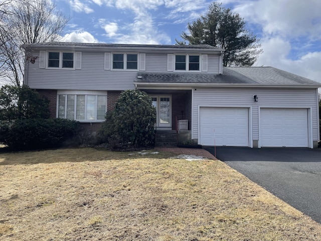 traditional home featuring a garage, brick siding, driveway, and a front lawn