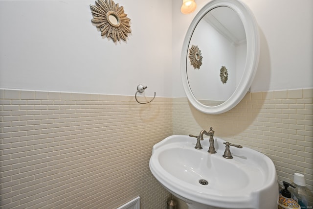 bathroom with tile walls, a sink, and wainscoting