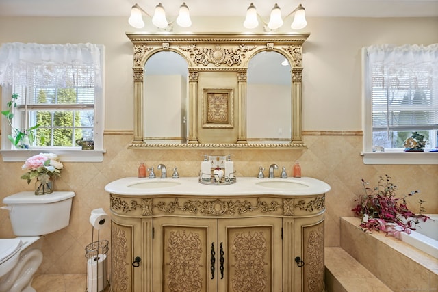 bathroom featuring double vanity, a sink, toilet, and tile walls