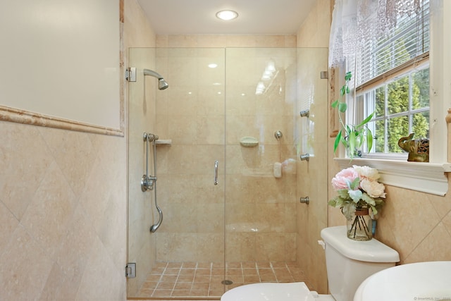 bathroom featuring a stall shower, tile walls, and toilet