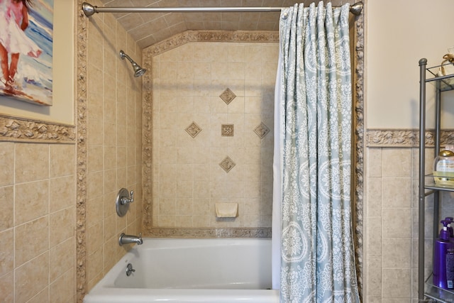 full bathroom featuring shower / bath combo, wainscoting, and tile walls