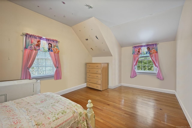 bedroom featuring vaulted ceiling, multiple windows, wood finished floors, and baseboards