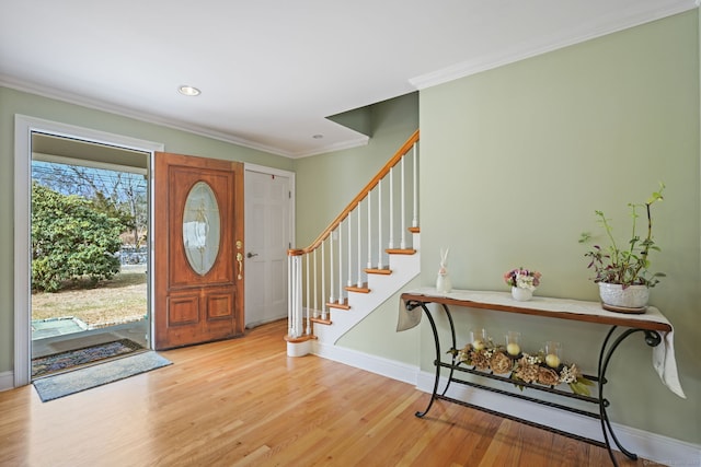 foyer featuring recessed lighting, wood finished floors, baseboards, stairs, and crown molding