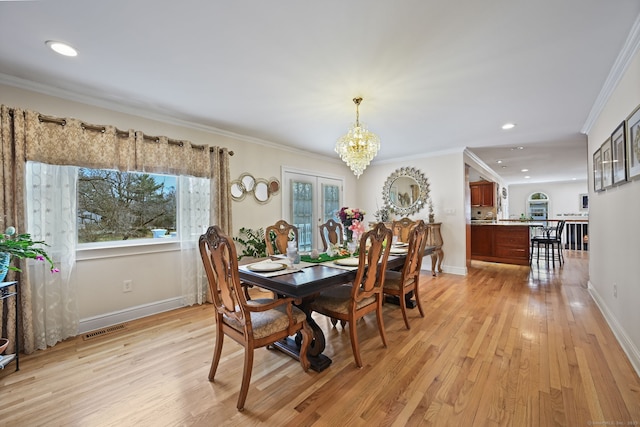 dining area featuring ornamental molding, light wood-type flooring, a chandelier, and visible vents