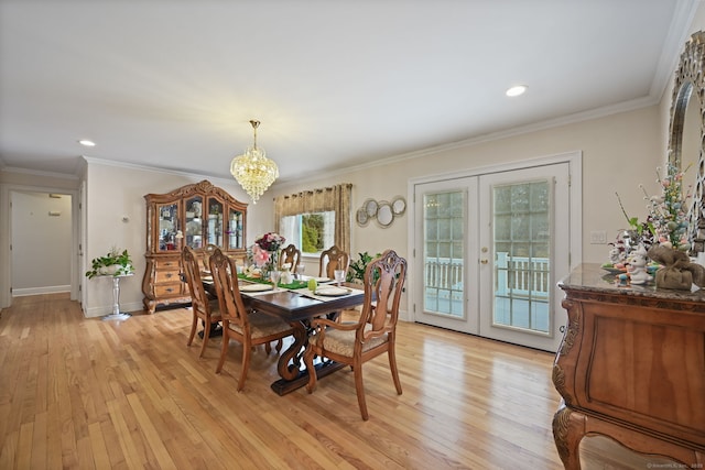 dining room with a notable chandelier, french doors, light wood-style flooring, and crown molding