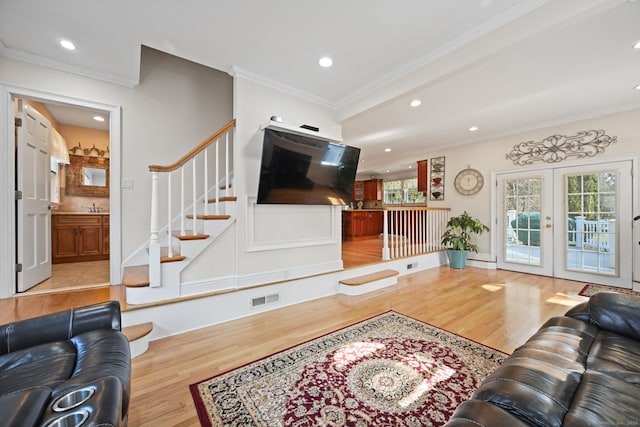 living room featuring wood finished floors, visible vents, french doors, stairway, and crown molding