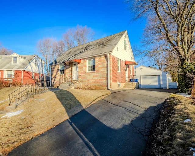 view of home's exterior with aphalt driveway, an outbuilding, brick siding, and a garage