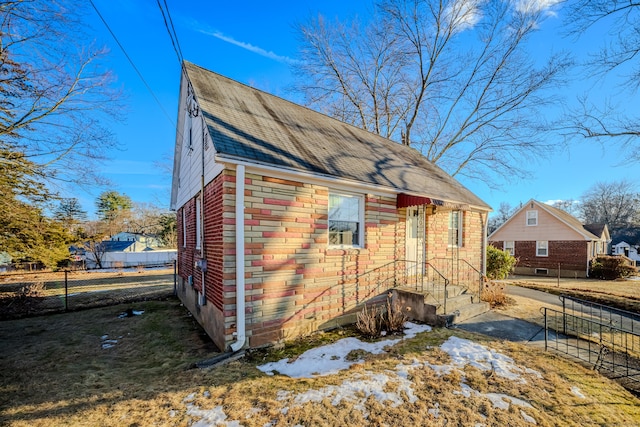 view of side of home with fence and roof with shingles