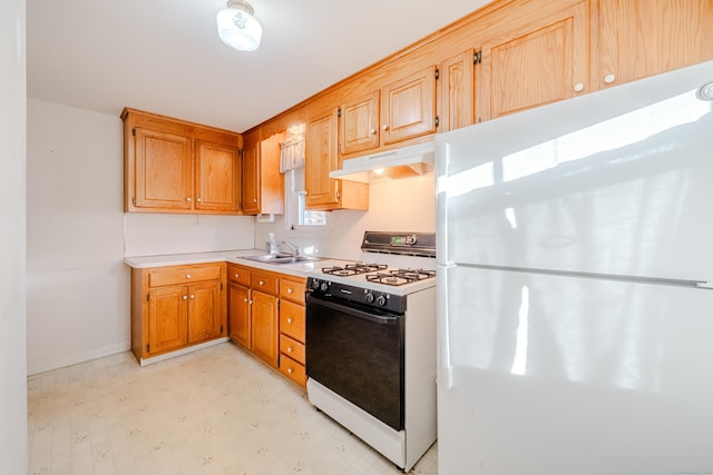 kitchen featuring light floors, light countertops, freestanding refrigerator, gas stove, and under cabinet range hood